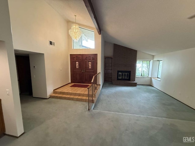 carpeted entryway with a notable chandelier, a brick fireplace, a textured ceiling, beamed ceiling, and visible vents