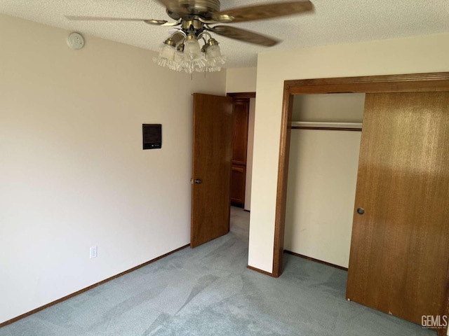 unfurnished bedroom featuring ceiling fan, light carpet, a textured ceiling, baseboards, and a closet