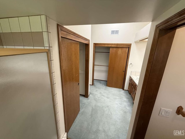 hall featuring light colored carpet and visible vents