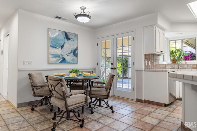dining room with stone finish flooring, baseboards, visible vents, and french doors