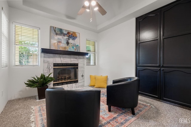 sitting room featuring a tray ceiling, light colored carpet, ceiling fan, and a tile fireplace