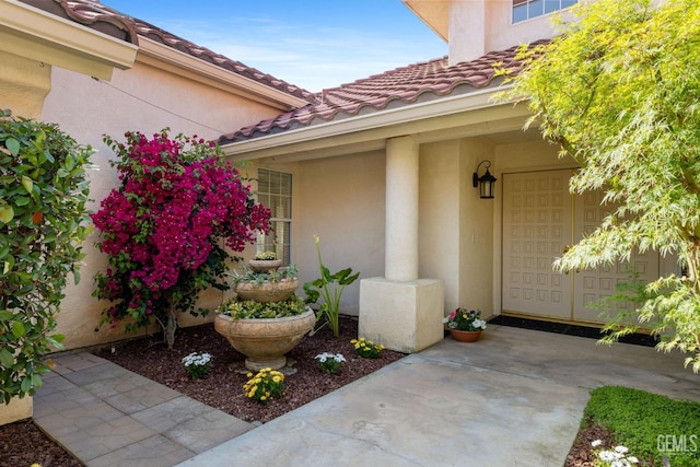 entrance to property featuring a tiled roof and stucco siding