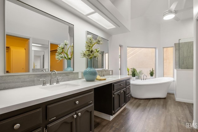 full bathroom featuring double vanity, a sink, a freestanding tub, and wood finished floors