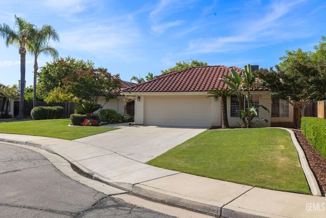 mediterranean / spanish-style home with driveway, a front yard, a garage, fence, and stucco siding