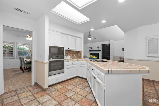 kitchen with visible vents, a ceiling fan, a peninsula, and black appliances