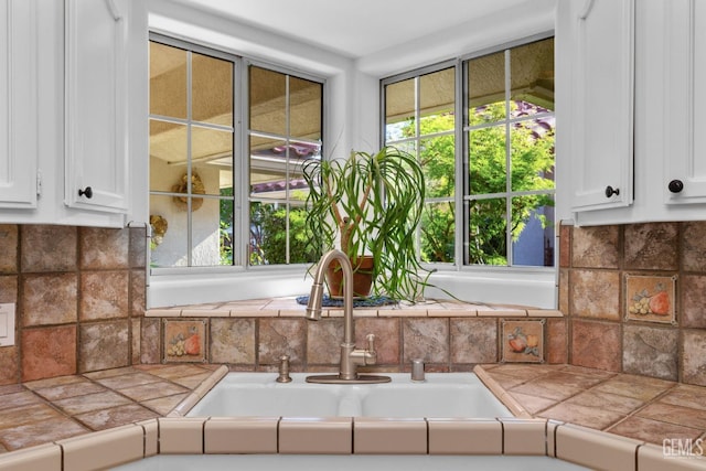 interior details with a sink, decorative backsplash, and tile counters