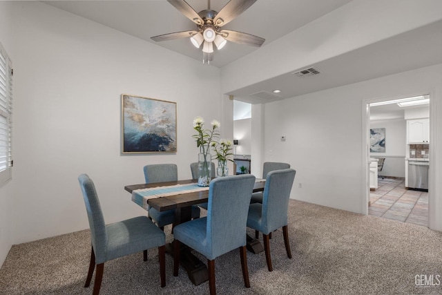 dining room with a ceiling fan, light colored carpet, and visible vents