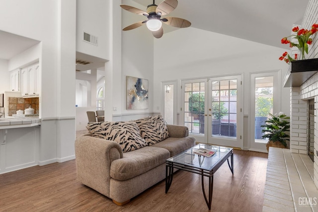 living room featuring visible vents, light wood-style flooring, ceiling fan, and high vaulted ceiling