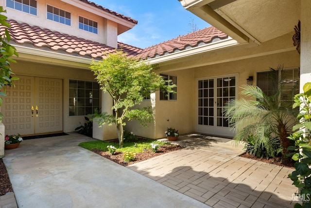 property entrance featuring a tiled roof, a patio area, stucco siding, and french doors