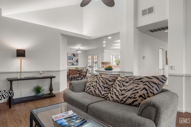 living area with visible vents, a ceiling fan, wood finished floors, and high vaulted ceiling