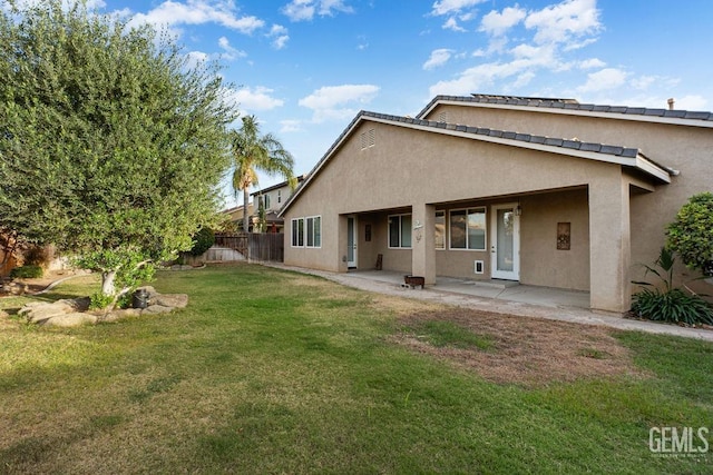 rear view of property featuring a lawn and a patio