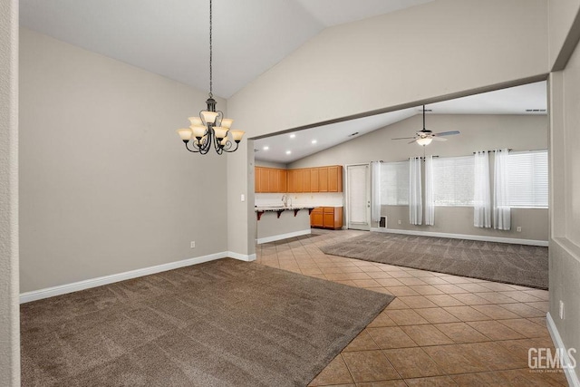 unfurnished living room featuring ceiling fan with notable chandelier, sink, light tile patterned floors, and lofted ceiling