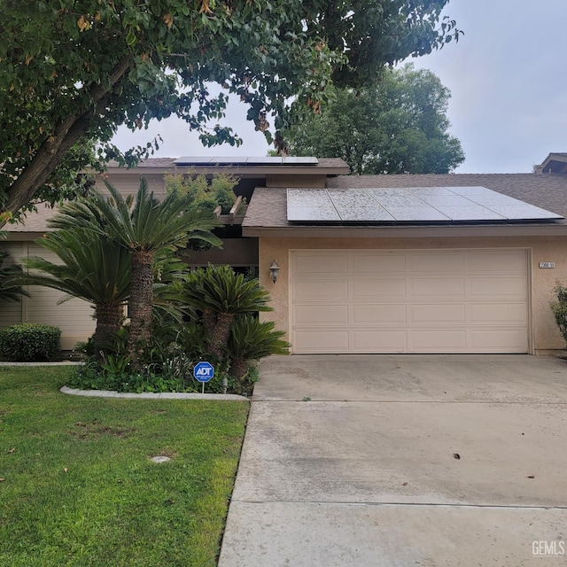 view of front facade with solar panels, a garage, and a front lawn