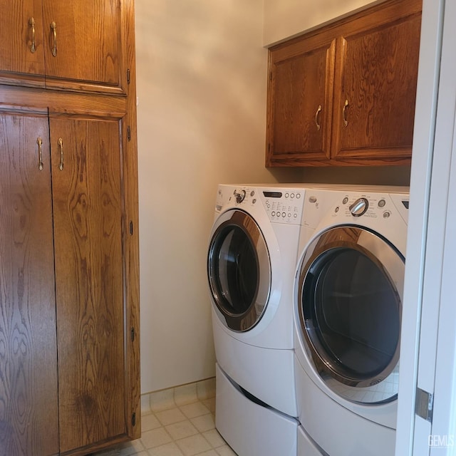 laundry area featuring light tile patterned flooring, cabinets, and independent washer and dryer