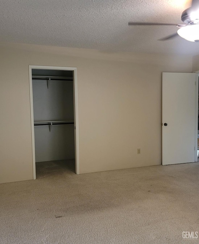 unfurnished bedroom featuring carpet flooring, ceiling fan, a textured ceiling, and a closet