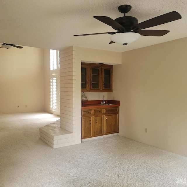 bar with light carpet, sink, and ceiling fan