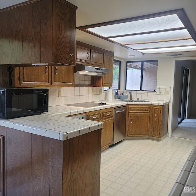 kitchen with sink, ventilation hood, kitchen peninsula, tile countertops, and stovetop