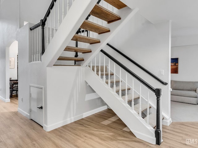 stairs with wood-type flooring and a towering ceiling