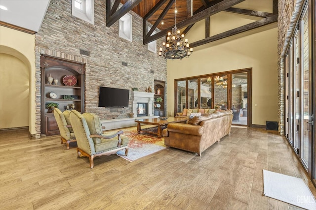 living room featuring a chandelier, high vaulted ceiling, light wood-type flooring, a large fireplace, and beamed ceiling