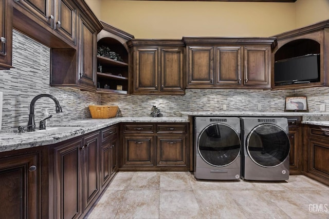 laundry room with cabinets, washer and clothes dryer, and sink