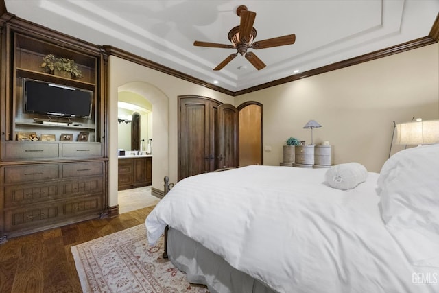 bedroom with ensuite bath, ornamental molding, dark hardwood / wood-style flooring, a raised ceiling, and ceiling fan