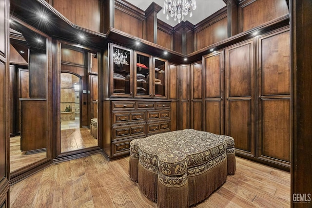 spacious closet featuring an inviting chandelier and light hardwood / wood-style floors