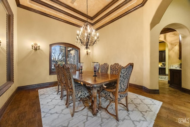 dining room featuring crown molding, wood-type flooring, a notable chandelier, and a tray ceiling