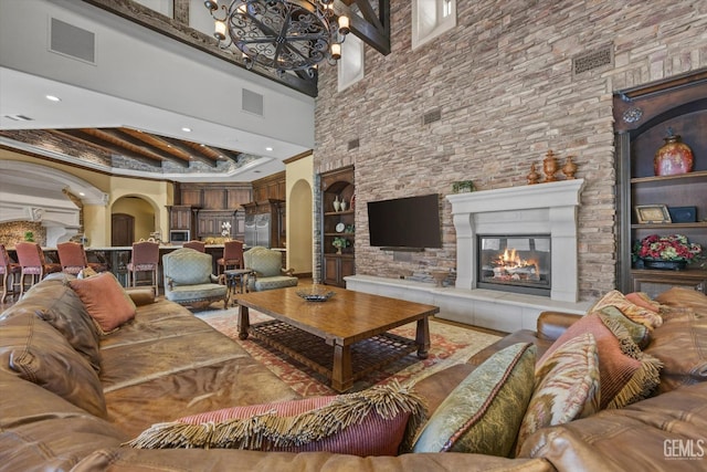 living room featuring a notable chandelier, a towering ceiling, and beamed ceiling