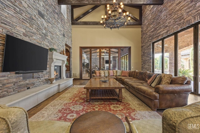 living room featuring a notable chandelier, a towering ceiling, a fireplace, and beamed ceiling