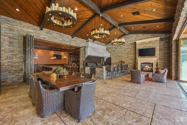 dining space with beam ceiling, high vaulted ceiling, wooden ceiling, and exterior fireplace