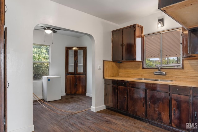 kitchen with dark brown cabinetry, ceiling fan, sink, and dark wood-type flooring