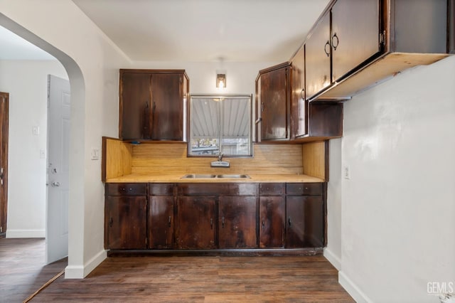 kitchen featuring tasteful backsplash, sink, dark wood-type flooring, and dark brown cabinets