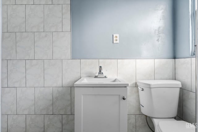 bathroom featuring vanity, toilet, and tile walls