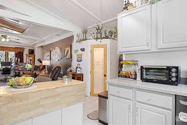 kitchen featuring ceiling fan, light tile patterned flooring, lofted ceiling, white cabinets, and ornamental molding