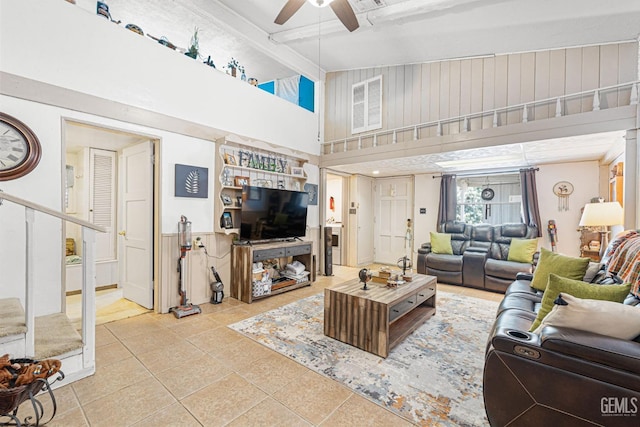 tiled living room featuring ceiling fan and a high ceiling