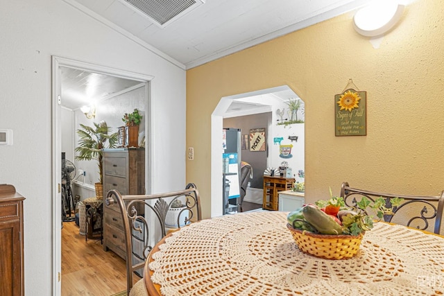 dining area with light wood-type flooring, ornamental molding, and vaulted ceiling