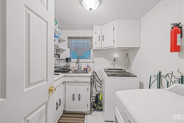 laundry room featuring cabinets, light tile patterned floors, sink, and washing machine and clothes dryer