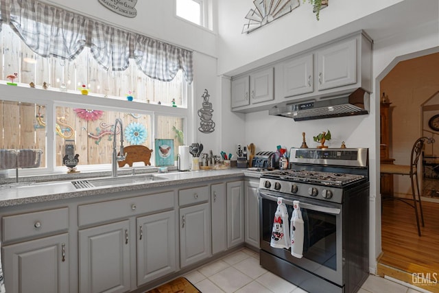 kitchen featuring light tile patterned floors, sink, gray cabinets, and stainless steel gas range