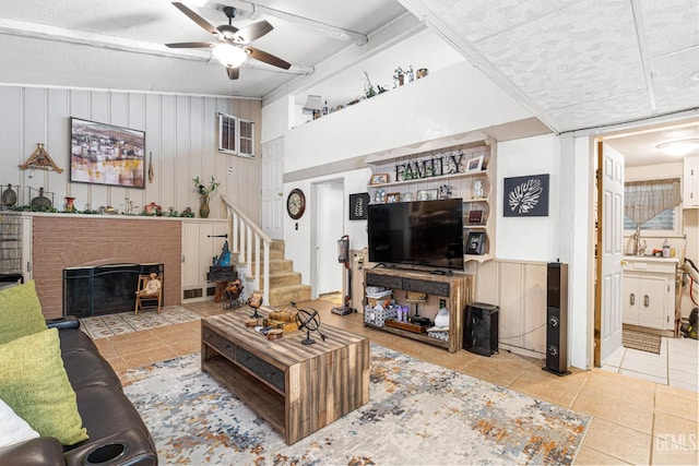 tiled living room featuring a brick fireplace, ceiling fan, and wooden walls