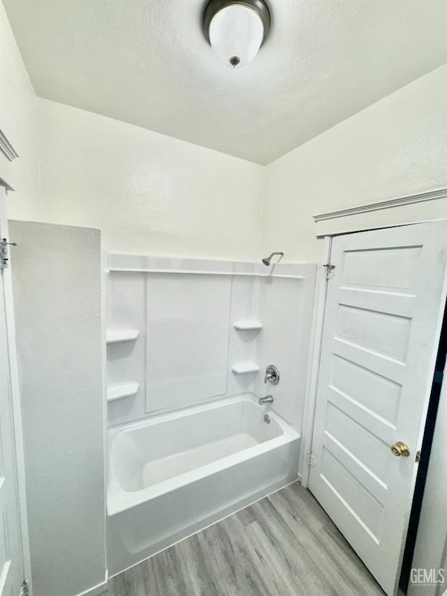 bathroom featuring hardwood / wood-style floors, shower / washtub combination, and a textured ceiling