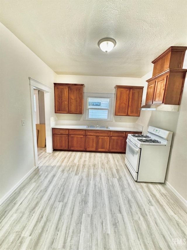 kitchen featuring white gas stove, a textured ceiling, and light hardwood / wood-style flooring