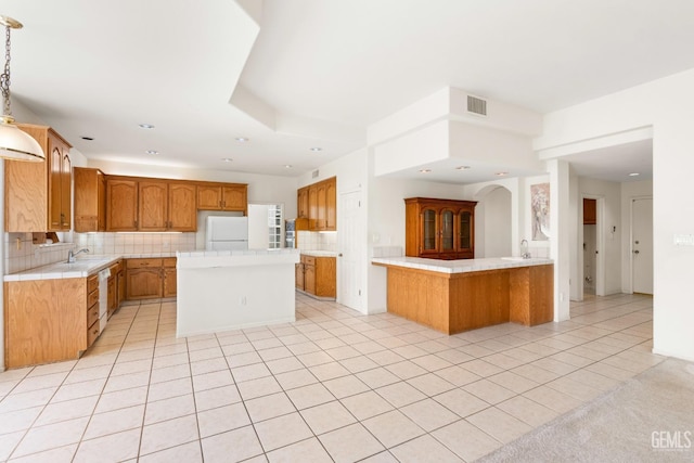 kitchen with light tile patterned floors, visible vents, a kitchen island, white appliances, and backsplash