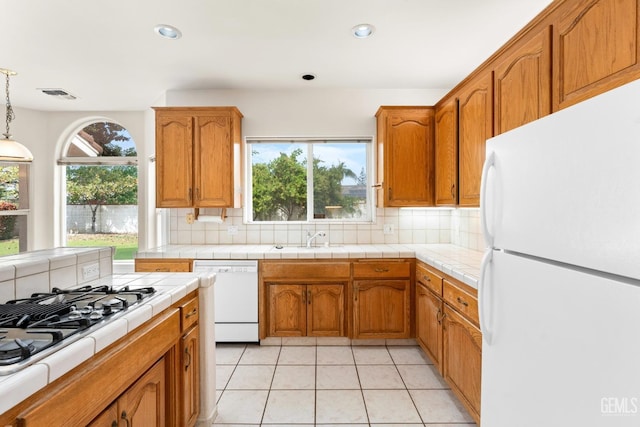 kitchen featuring brown cabinets, visible vents, white appliances, and decorative backsplash