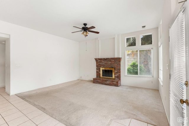 unfurnished living room featuring a brick fireplace, light tile patterned floors, a ceiling fan, and light carpet