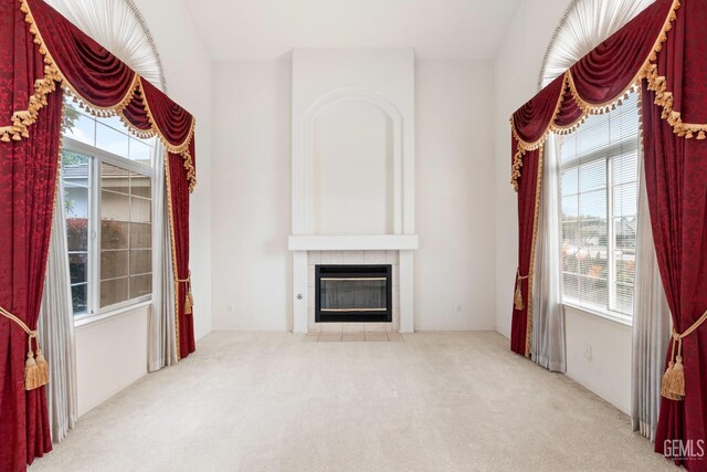 unfurnished living room featuring a tile fireplace and carpet