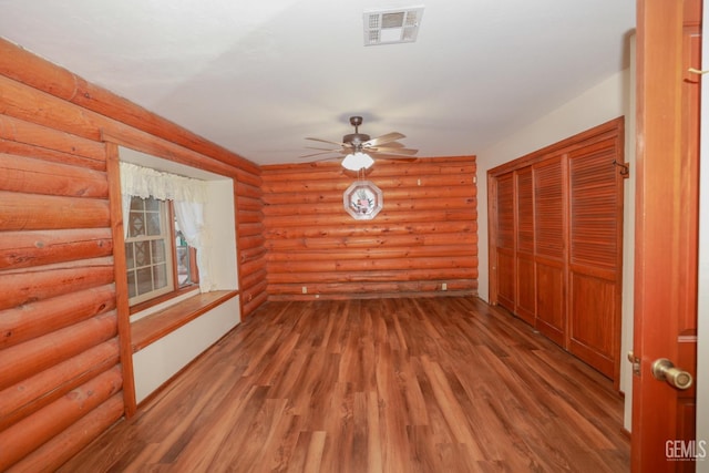 unfurnished room featuring rustic walls, ceiling fan, and hardwood / wood-style floors