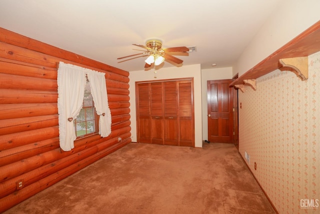 unfurnished bedroom with light carpet, a closet, rustic walls, and ceiling fan