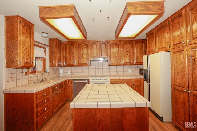 kitchen featuring dishwasher, a center island, sink, tasteful backsplash, and white refrigerator with ice dispenser