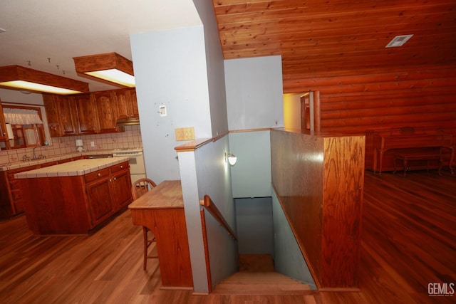 kitchen with log walls, decorative backsplash, a center island, and stove