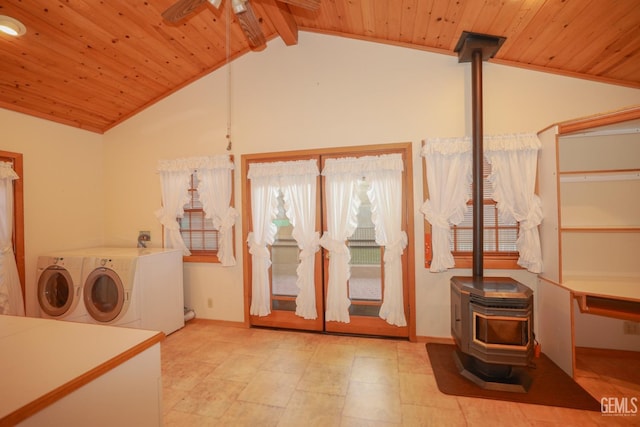 interior space featuring ceiling fan, a wood stove, wood ceiling, and separate washer and dryer